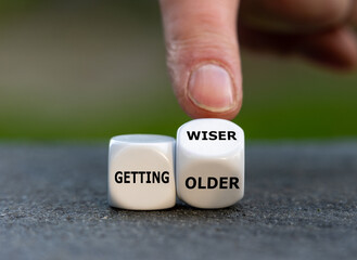 Hand turns dice and changes the expression 'getting older' to 'getting wiser'.