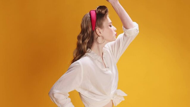 Fixing. Beautiful smiling young blonde girl in white shirt posing with tool over yellow background. Concept of retro fashion, beauty, attraction, 50s, 60s. Pin-up style. Vintage