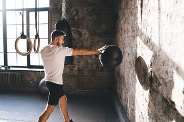 Athletic man doing medicine ball chest pass exercise during workout at gym