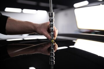 employee of the car detailing studio removes minor dents from the roof of the car