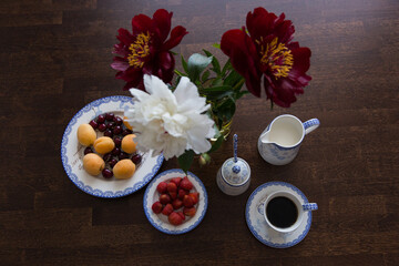 Obraz na płótnie Canvas Breakfast with coffee, fruits, milk and peony on wooden table