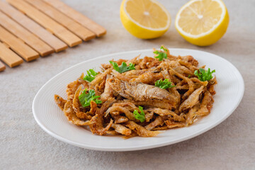 Crispy fried small fish on white plate