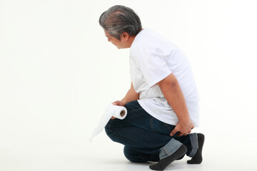 Asian fat man sitting on white floor holding toilet paper He used his other hand to hold his buttocks. The concept of health care for obese people. hemorrhoids