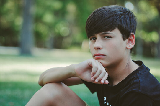 Portrait of a teenage boy sitting in Parque del Retiro in summer, Madrid, Spain