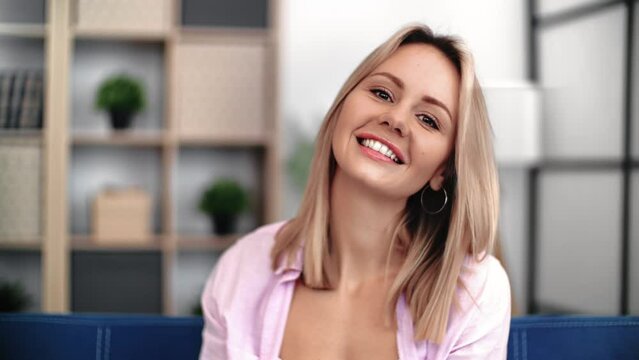 Portrait cute young blonde woman with perfect skin and natural beauty smiling at cozy living room