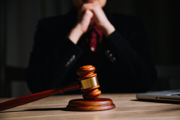 Justice and law concept.Male judge in a courtroom with the gavel, working with, computer and docking keyboard, eyeglasses, on table in morning light
