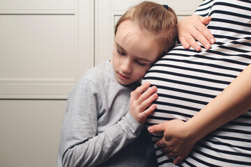 Pregnant mother and son at home. Cute boy with mom spending time together at home. Child boy hugging his mother pregnant tummy.