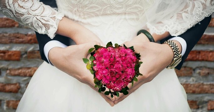 A bouquet of roses on the hand of  her and him in the wedding day.