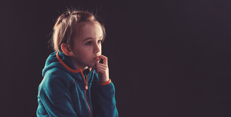 Sad child thinking about his problems. Emotional child portrait. Nervously kid bits his fingernail....