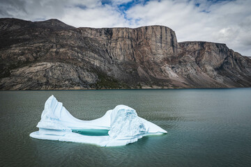 Big blue iceberg reflecting in water floats in the sea by Broughton Island, Nunavut, Canada. auyuittuq national park