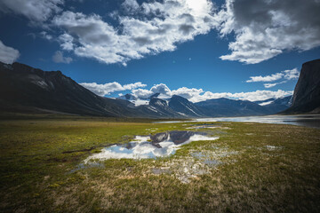 Water front view of mountains on Akshayuk Pass, Buffin Island, Canada. Pond reflections