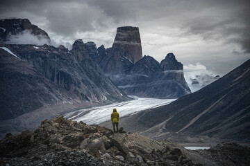 A man standing on a stone cliff in Akshayuk Pass, Nunnavut, Canada. Foggy mountains, cloudy morning...