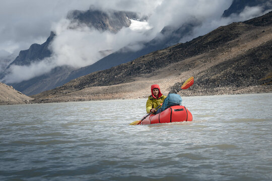 A man rowing packraft on Summit Lake, Akshayuk Pass, Baffin Island, Canada