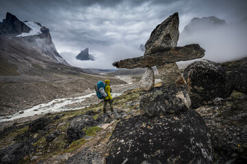 Hiker walking through remote arctic valley Akshayuk Pass, Baffin Island, Canada . Dramatic arctic landscape.