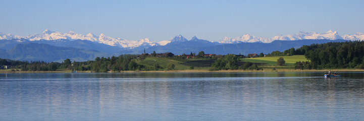 Shore of Lake Pfaffikon in spring, Wetzikon and snow capped mountains.