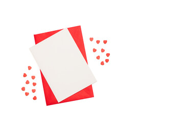 Sobre rojo y una tarjeta en blanco junto a pequeños corazones rojos sobre un fondo blanco liso y aislado. Vista superior y de cerca. Copy space