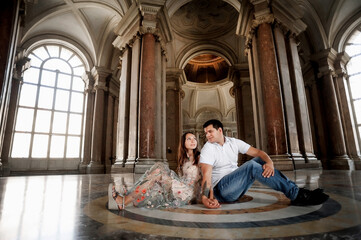 Naklejka premium A young couple is hugging in the hall of a large historic building. Tender relations between a man and a woman. A walk in historical places. Good weather for a walk. Meeting and excursion.