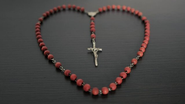 The Catholic rosary beads are laid out in the shape of a heart.