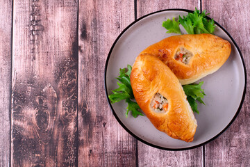 Rasstegai buns with red fish, rice and roasted onion on wooden table. Russian yeast dough bakery product. Top view - obrazy, fototapety, plakaty