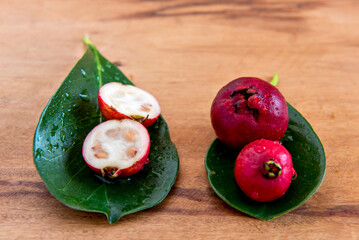 Red Cattley guava fruit and leaves on wooden bottom (Psidium cattleyanum)