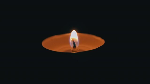 Paraffin Candle Burns In The Dark With A Yellow Flame. A Large Fire In A Wax Candle Burns Yellow. There Is No Light In The House, Heat From A Candle. Poverty, War, A Moment Of Silence.