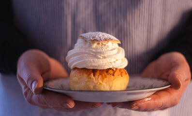 A women holding a small plate with a semla