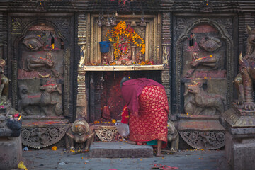 Woman pray for Hinduism god statue in Bhaktapur Durbar Square, Nepal