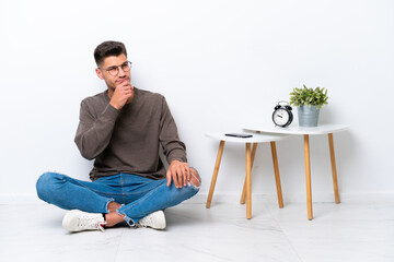 Young caucasian man sitting in his home isolated on white background and looking up