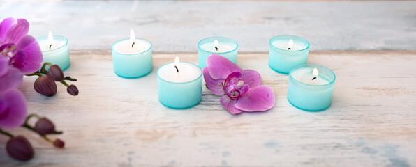 Spa decoration with purple orchids and candle lights on gray vintage wood. Background for wellness...