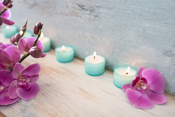 Spa decoration with purple orchids and candle lights on gray vintage wood. Background for wellness...