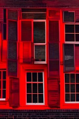 View of the window in red light at night. Red light district windows. Isolated on a black background. Red light from the window. The red window shines mystically at night - generative ai