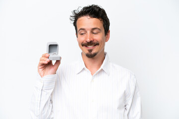 Young man holding a engagement ring isolated on white background with happy expression