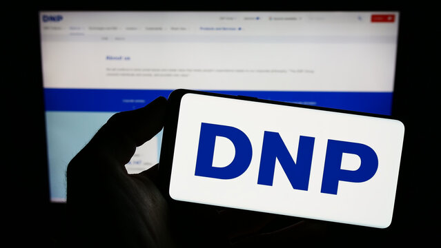 Stuttgart, Germany - 01-28-2023: Person holding smartphone with logo of Japanese company Dai Nippon Printing Co. Ltd. on screen in front of website. Focus on phone display.