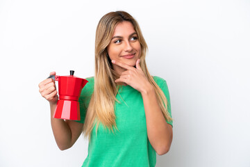 Young Uruguayan woman holding coffee pot isolated on white background thinking an idea and looking side