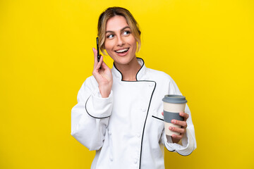 Uruguayan chef woman isolated on yellow background holding coffee to take away and a mobile