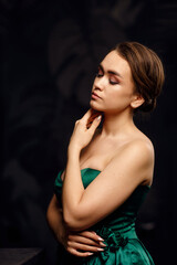 A girl in a green dress on a dark background