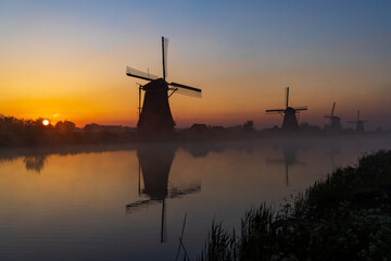 Fototapeta na wymiar Traditional Dutch windmills with a colourful sky just before sunrise in Kinderdijk, The Netherlands
