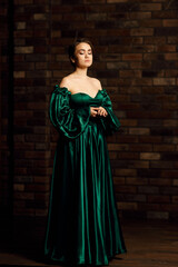 Full-length portraits of a girl in a green dress against a brown brick wall