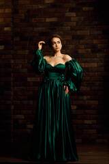 Fototapeta na wymiar Full-length portraits of a girl in a green dress against a brown brick wall