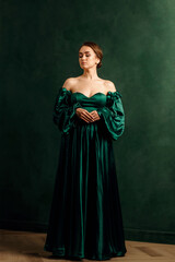 a girl in a green dress standing against a green wall