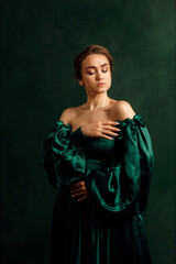 waist portrait of a girl in a green dress standing against a green wall