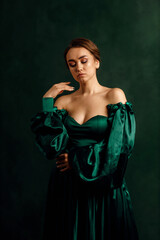 waist portrait of a girl in a green dress standing against a green wall
