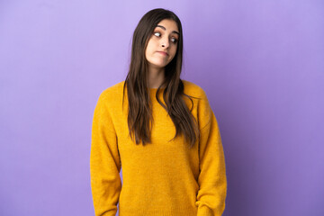 Fototapeta premium Young caucasian woman isolated on purple background making doubts gesture looking side