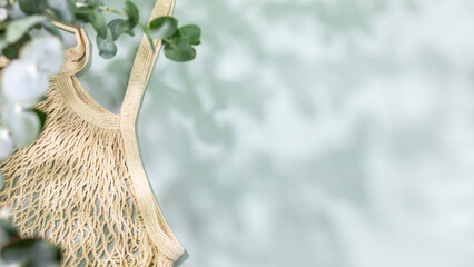 Eco friendly shopping concept. Environment, sustainable composition with natural textile bag on blue background with green leaves and shadows. Flat lay, copy space