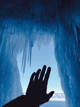 Silhouette of an outstretched hand reaching for icicles, Lake Baikal, Siberia, Russia