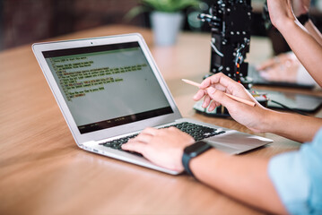 Close up photo of IT programmer coding arduino for robotic arm, Male specialish working with friends at technology and inovation learnig center.