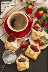 Board with delicious cookies for Valentine's Day celebration on a black background, with a red cup of hot drink, decorated with powdered sugar, nuts and fresh berries .