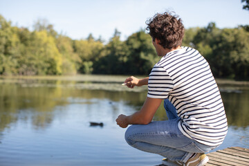a young man sitting near a nice lake