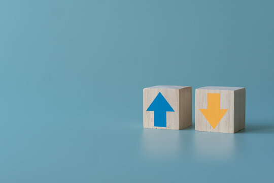 Wooden block with up and down arrow concept of differentiation or Opposite direction. Blue arrow up for positive but yellow arrow down for negative. Business trend concept using wooden blocks.
