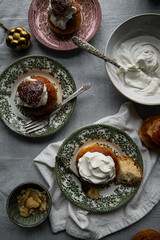 Homemade semlor buns with frangipane and whipped cream on vintage plates.